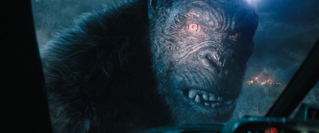 Kong, an enormous ape, looks into an aircraft cockpit window, a spotlight illuminating his gigantic eye, in Monarch: Legacy of Monsters